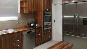 Uma cozinha com armários de madeira, geladeira de aço inoxidável, lava-louças e forno.
