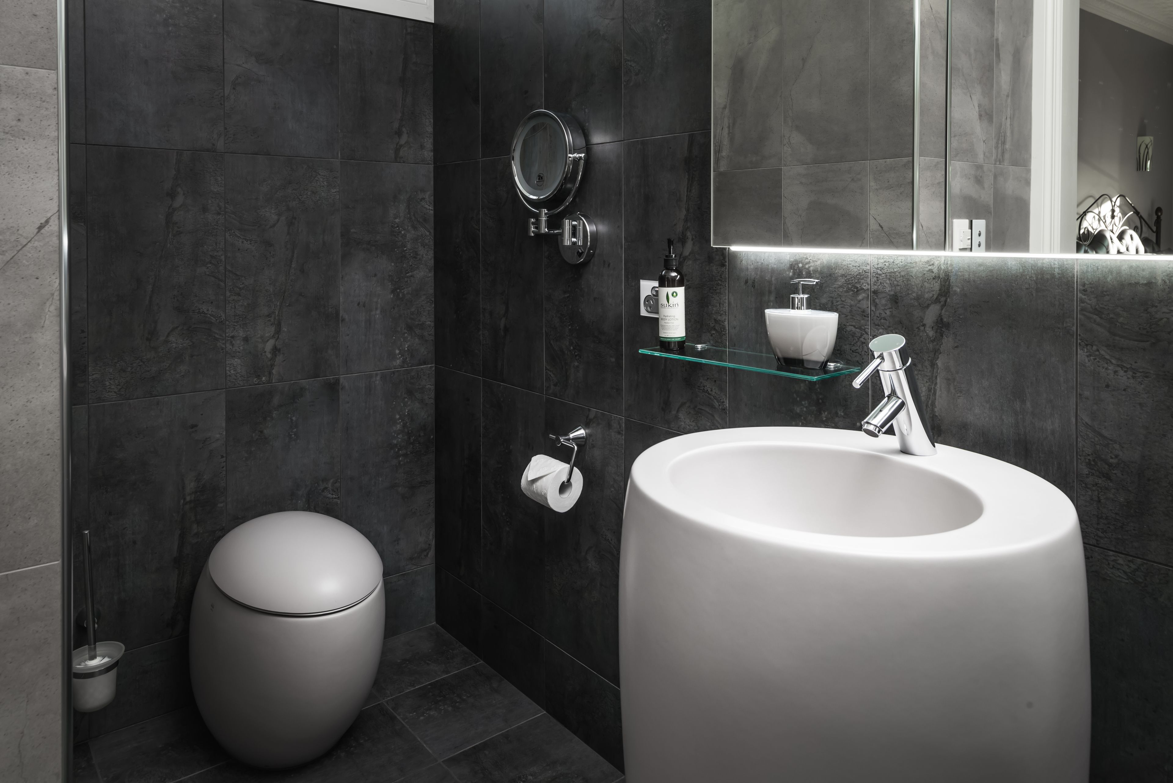 Ein modernes Badezimmer mit einem großen Waschbecken, einer Toilette und einem Spiegel.
