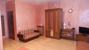 A living room with a sofa, a TV, a wardrobe, and a small cabinet. - Guest House na Slobodskoy (St. Petersburg)