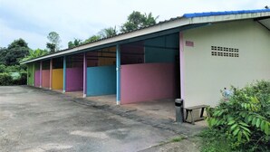 Una hilera de cabañas individuales coloridas con un espacio al aire libre techado.