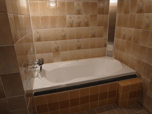 A bathroom with a bathtub, tiled walls, and a shower area. - NUDA by H-Seven - Adults Only (Yokohama)