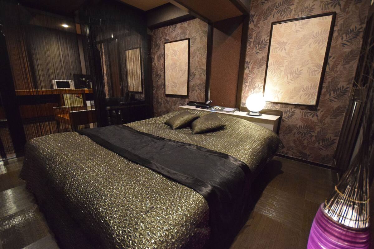 Une chambre à coucher moderne avec un grand lit, une table de chevet et une lampe.