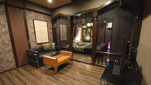 A modern room with a sofa, a wooden coffee table, and a desk. - NUDA by H-Seven - Adults Only (Yokohama)