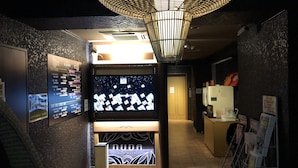 A hotel lobby with a digital display, a reception desk, and a staircase. - NUDA by H-Seven - Adults Only (Yokohama)