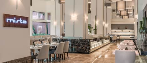 A modern restaurant interior with marble flooring, high ceilings, and pendant lighting.