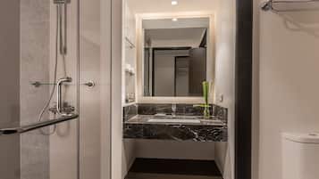 A modern bathroom with a glass shower enclosure, a marble sink, and a built-in toilet.