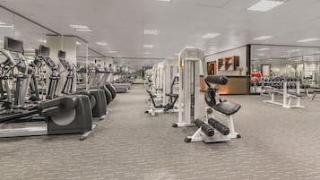 A gym with treadmills, weight machines, and a mirrored wall.