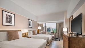 A hotel room with two beds, a desk, a TV, and framed pictures on the wall. - Seda Ayala Center Cebu City (Cebu City)