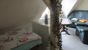 Une chambre avec un lit simple, une petite table, une chaise et un canapé.