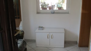 Une pièce avec une fenêtre, une armoire blanche et un sol carrelé.