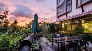Une terrasse extérieure avec un sol en bois, des tables, des chaises et des plantes en pot.