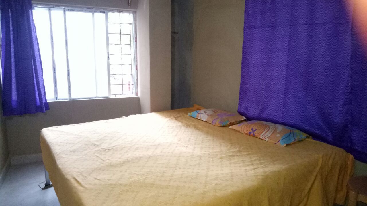 Una stanza con un letto, una finestra con sbarre e tende viola.