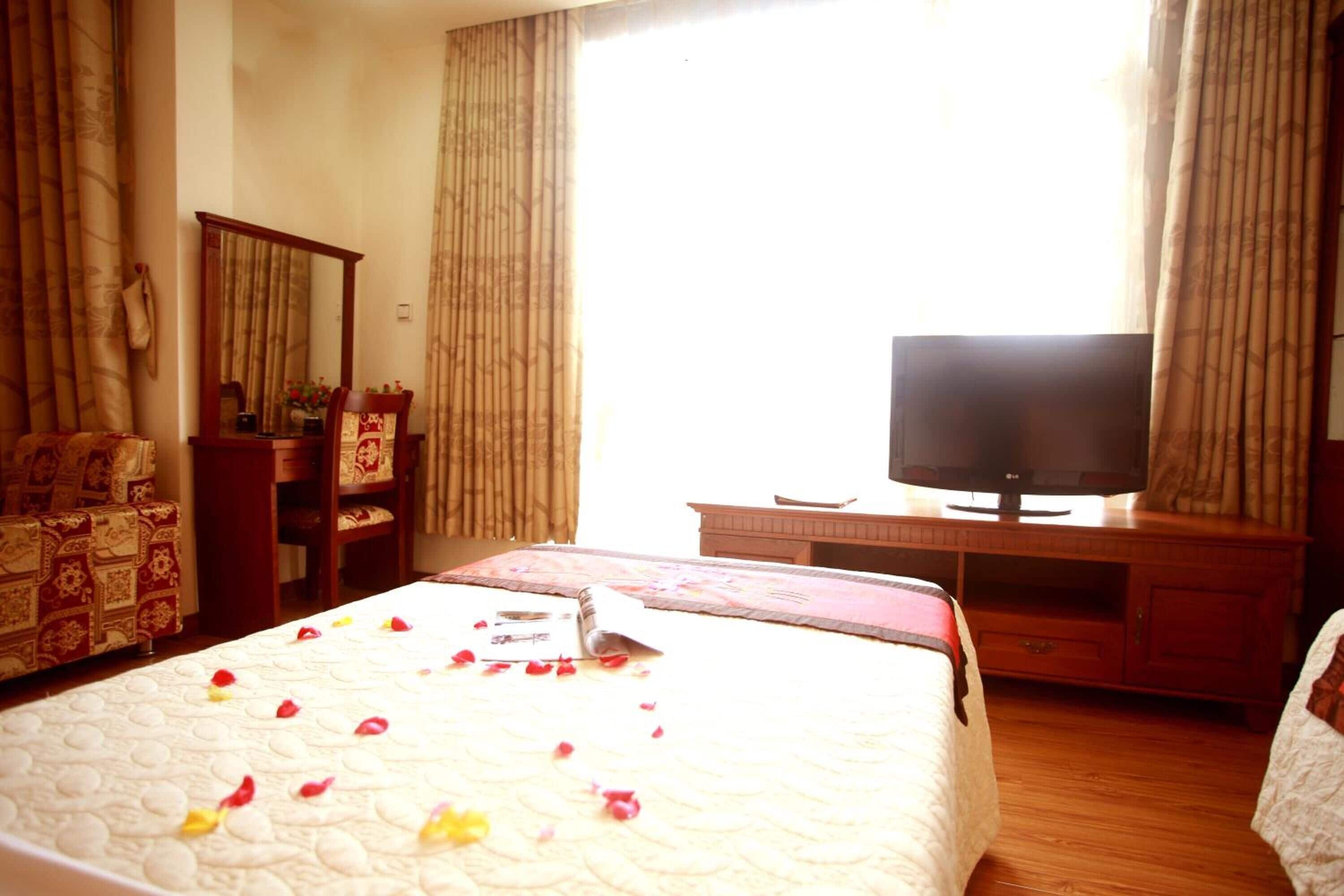 A hotel room with a bed, a television, a desk, and a chair.
