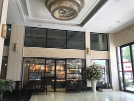 Um saguão de hotel moderno com fachada de vidro ampla, área de estar e um lustre decorativo.