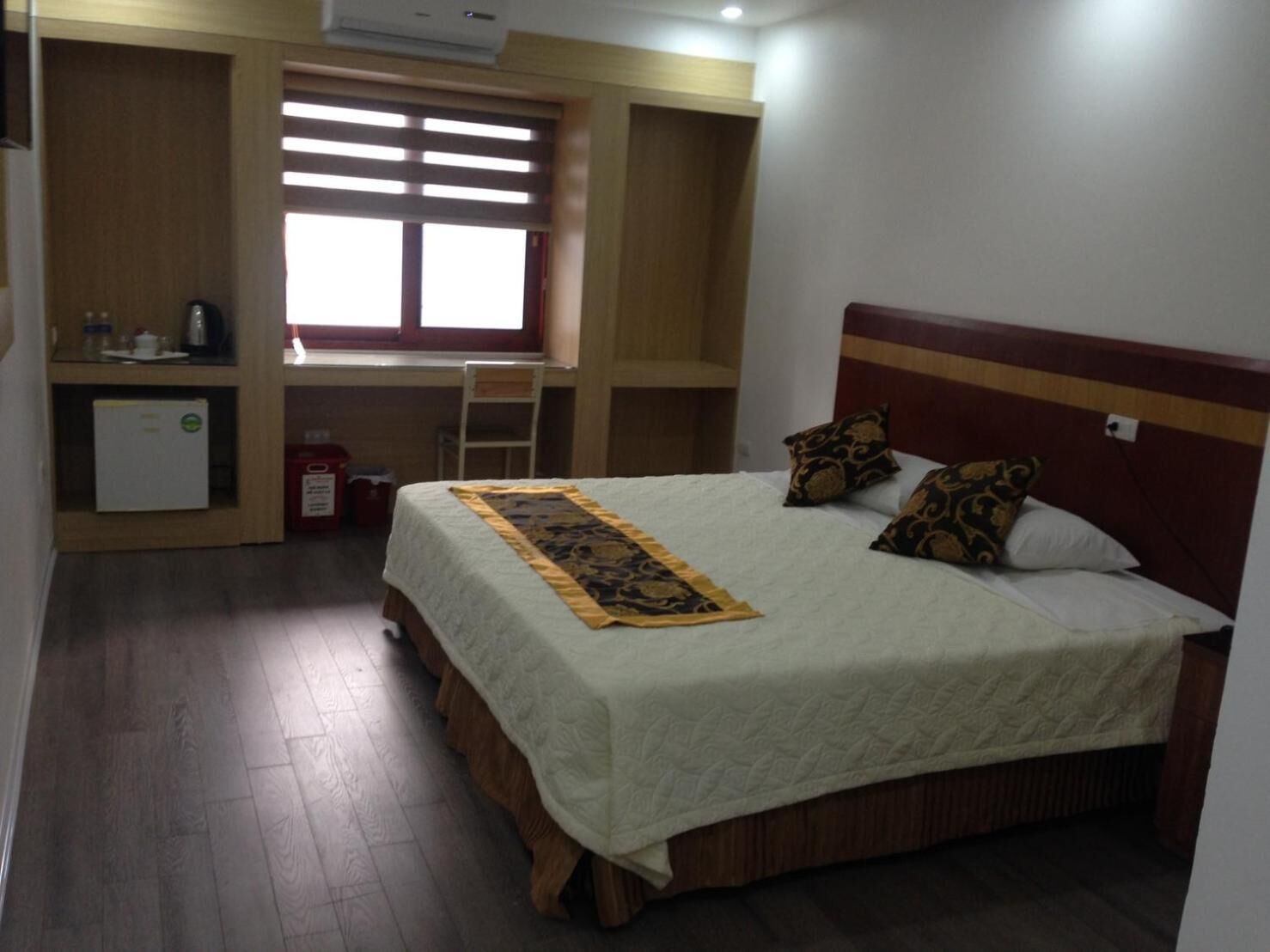 A bedroom with a bed, a desk, and a small refrigerator.