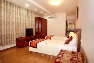 Quarto de hotel com duas camas, televisão, guarda-roupa e ar condicionado.