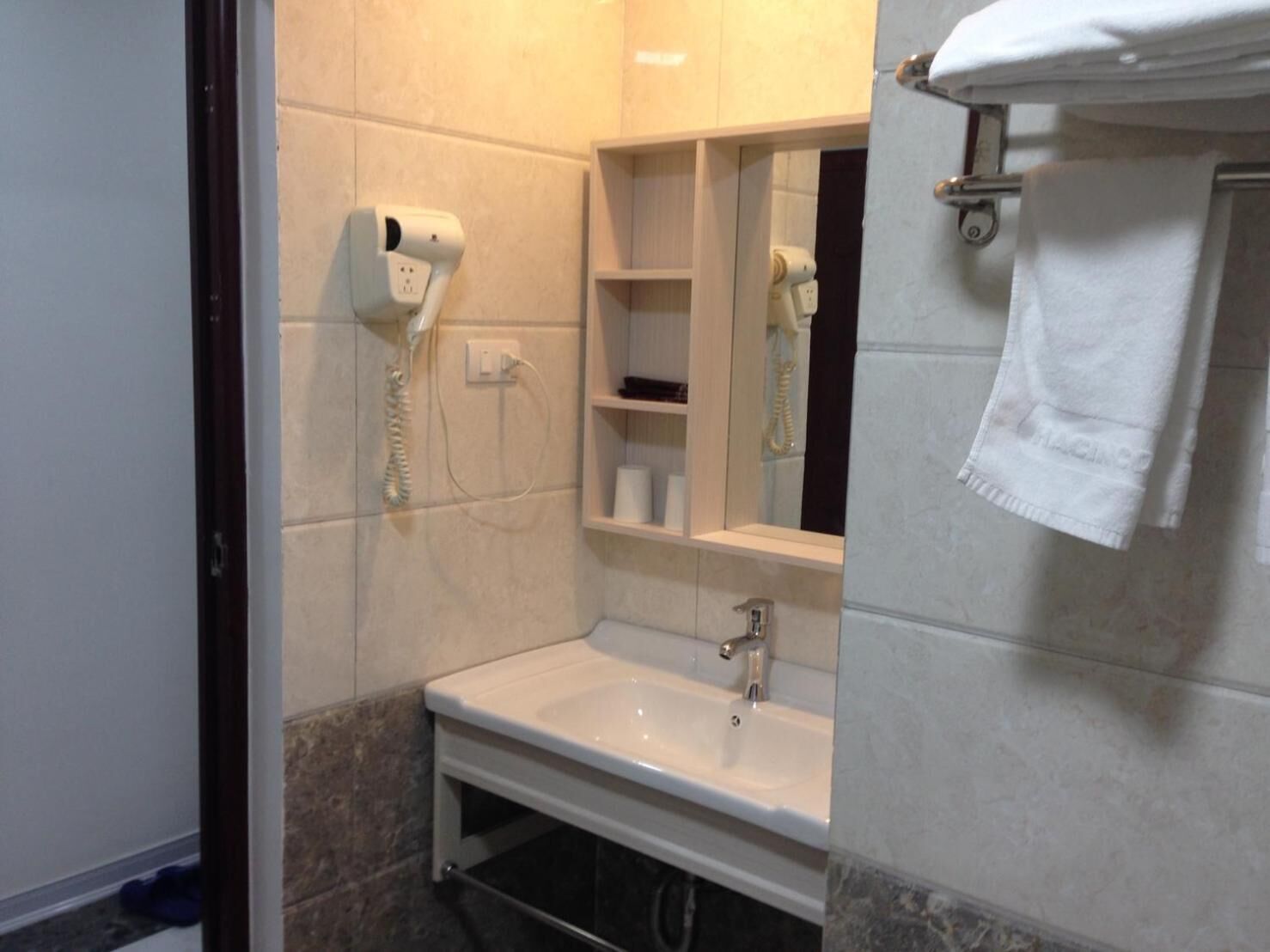 A bathroom with a sink, a mirror, a towel rack, and a hairdryer.