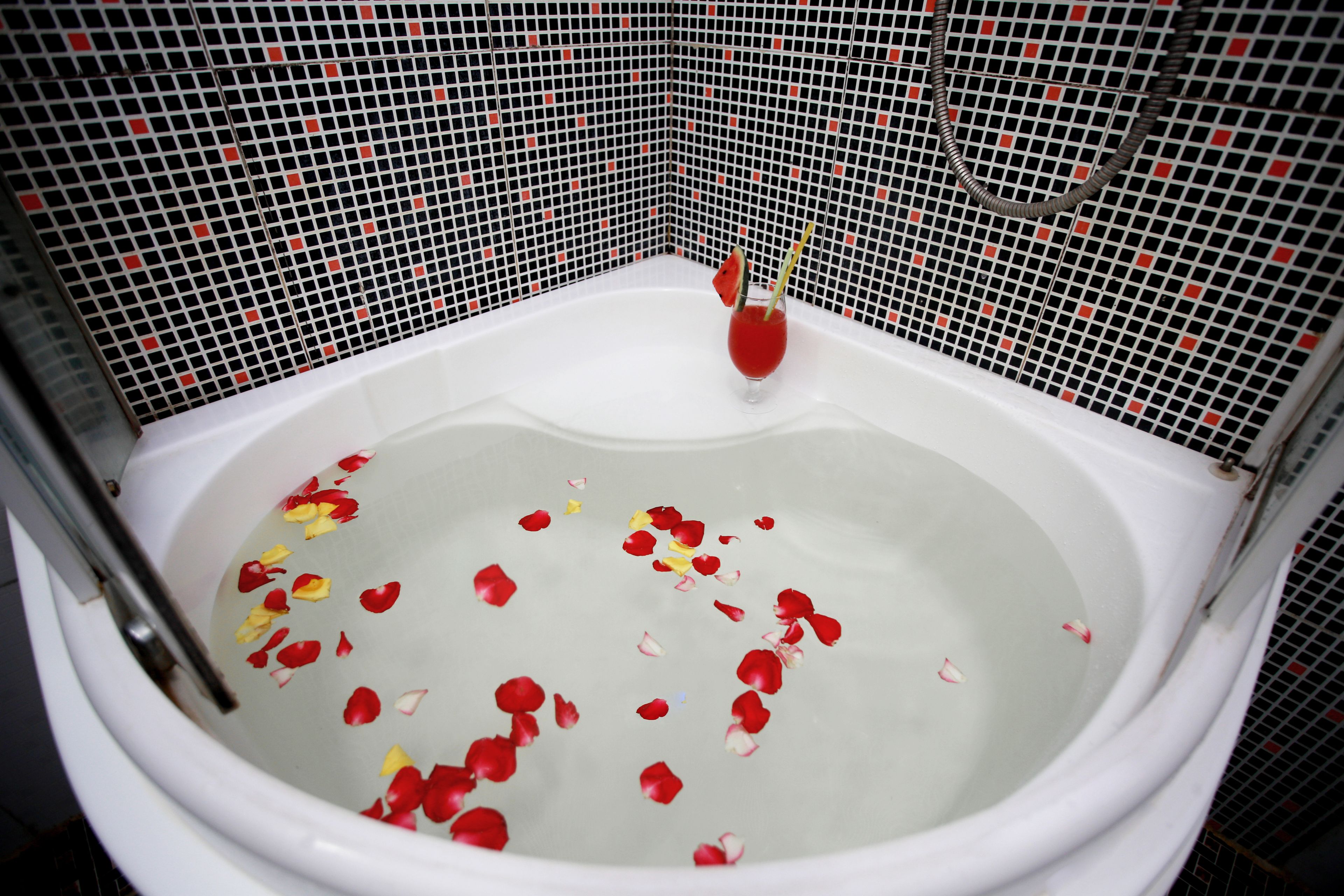 Una bañera llena de agua y pétalos de rosa.
