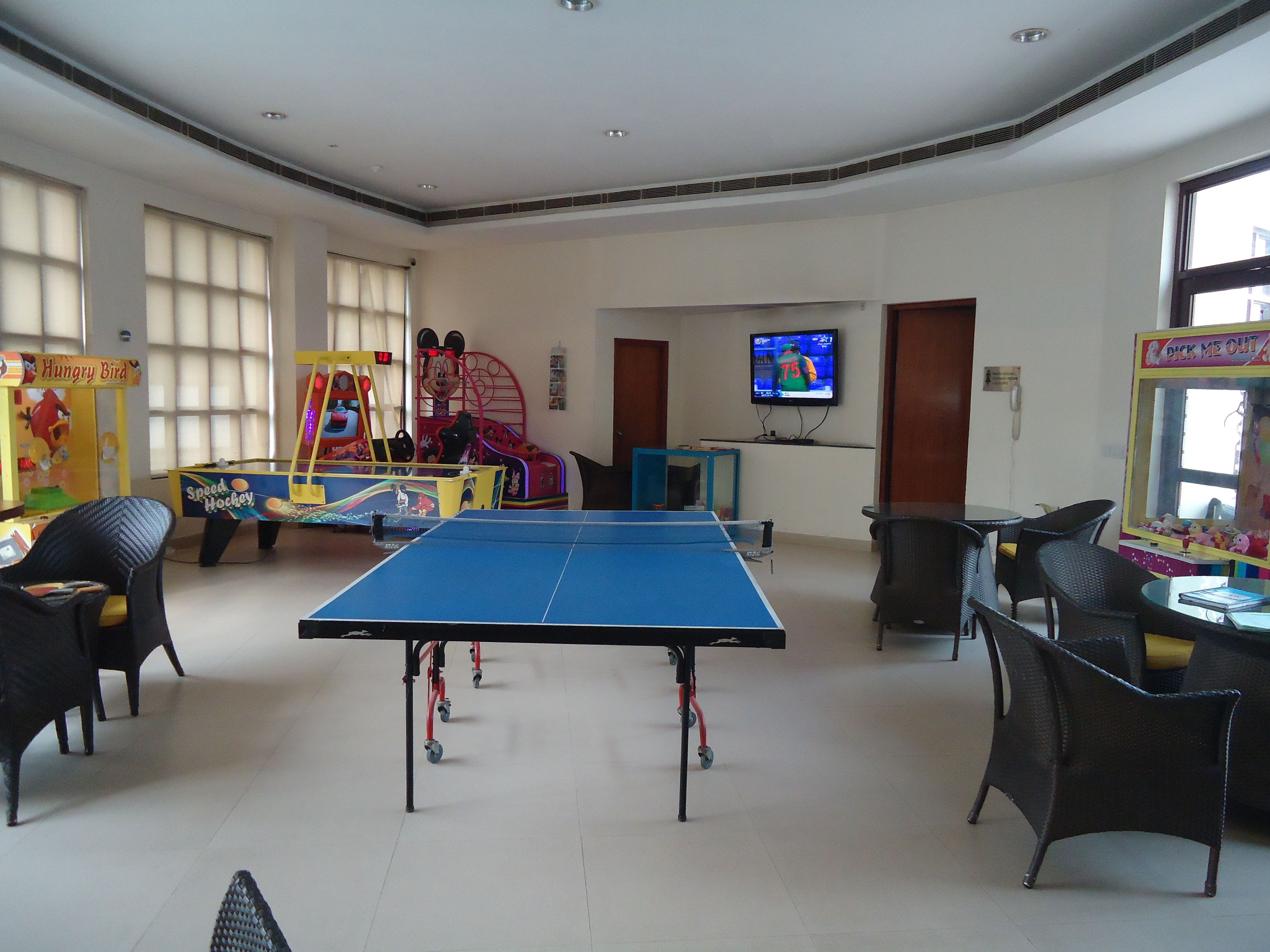 Una habitación con mesa de ping pong, zona de juegos infantiles y televisor.