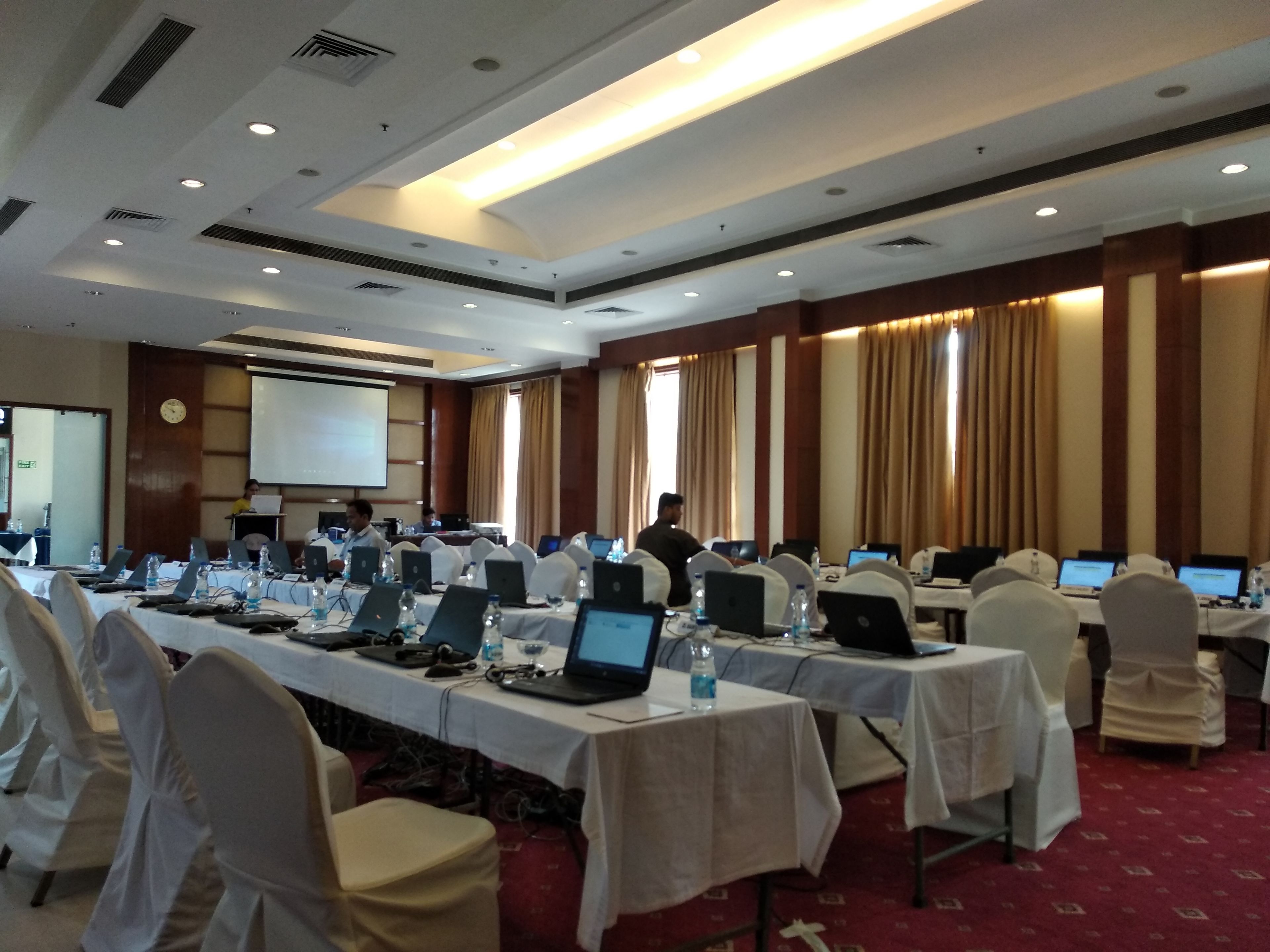 Una sala de conferencias con varias mesas, computadoras portátiles y sillas.
