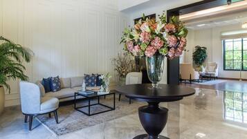 A modern living room with a sofa, coffee table, and a large floral arrangement.