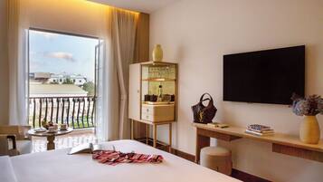 A hotel room with a bed, a desk, a TV, a window with curtains, and a balcony.