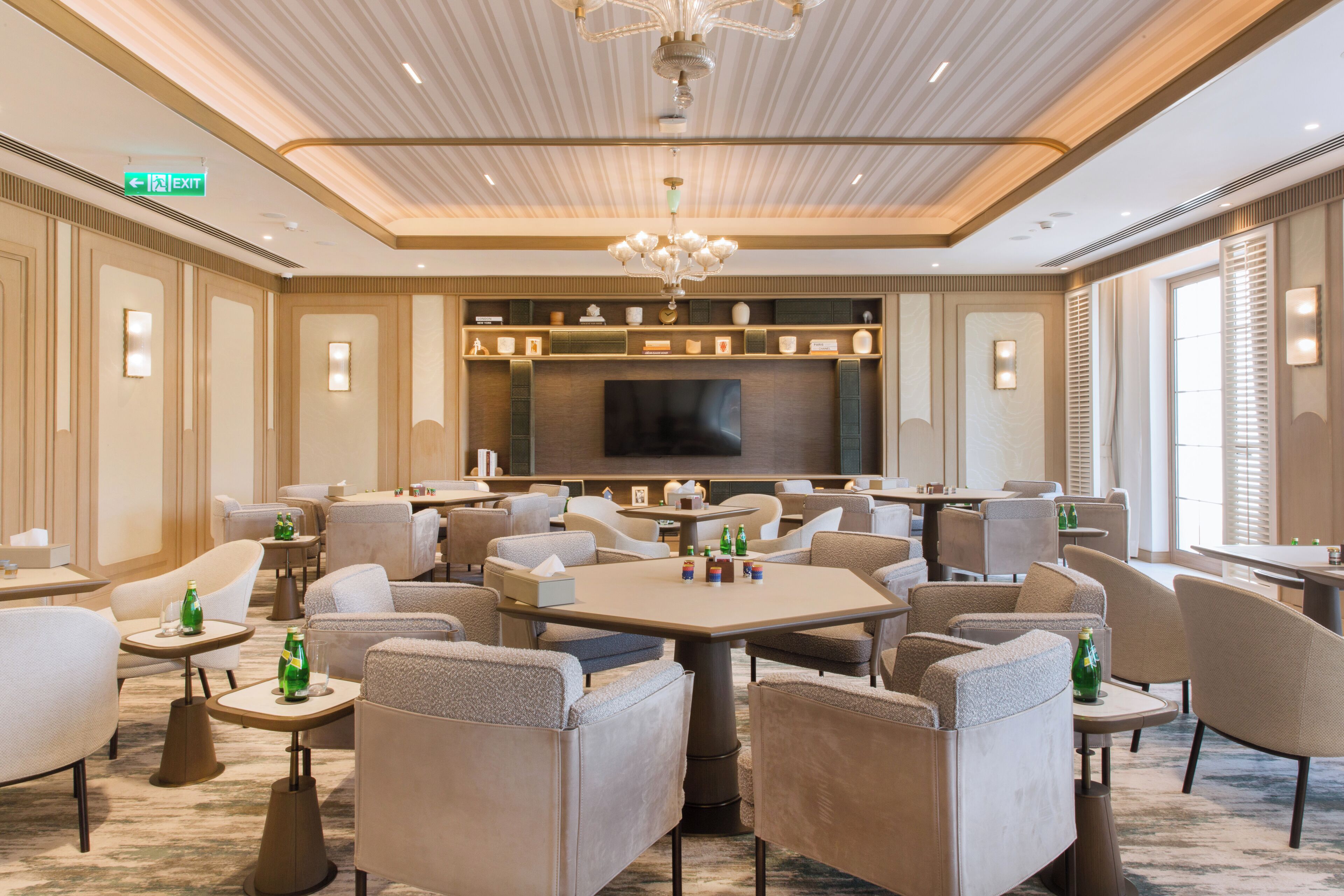 A hotel conference room with a large table, multiple chairs, a television, and a chandelier.