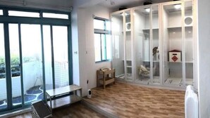 Quarto moderno com grandes janelas, piso de madeira e armário com portas de vidro.