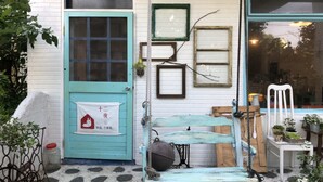 Exterior rústico com uma porta azul-turquesa, uma parede branca e um banco de madeira.