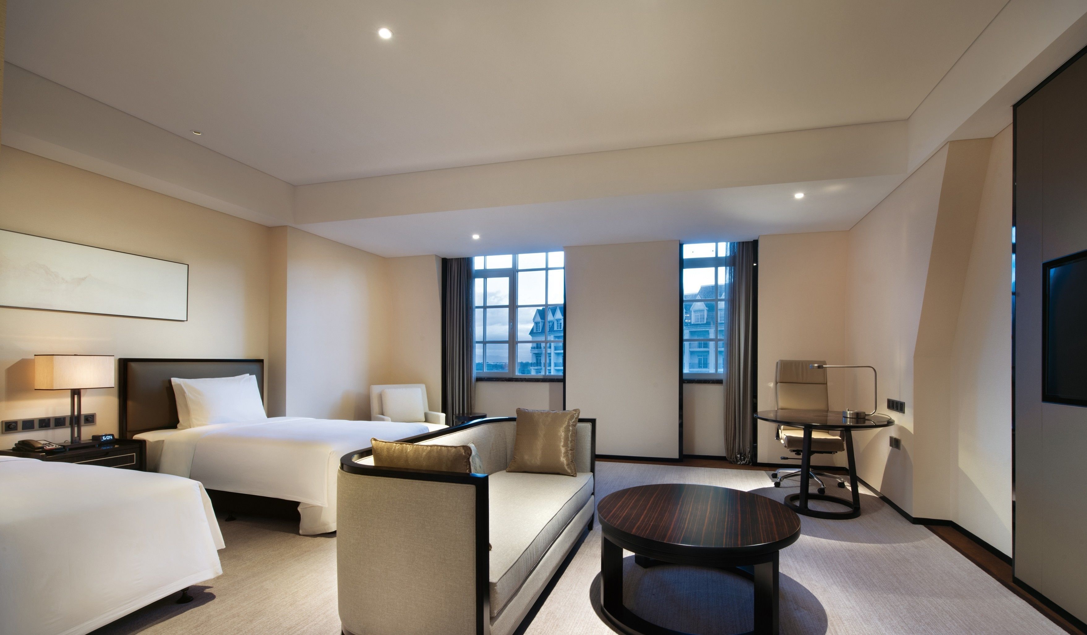A hotel room with a bed, two armchairs, a small table, and a TV.
