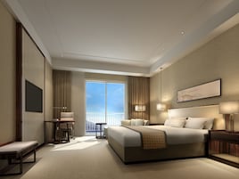 Una habitación de hotel moderna con una cama grande, un escritorio y una silla. Hay una ventana con vista al cielo y un balcón.