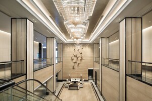 Un interior moderno con una zona de estar central, barandillas de vidrio y un elemento decorativo en la pared.