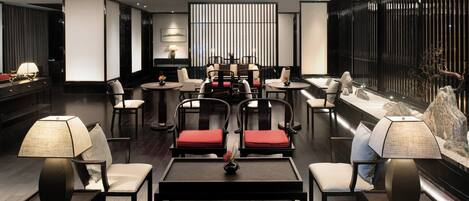 A modern lounge area with multiple seating options, including sofas and chairs, arranged around tables.