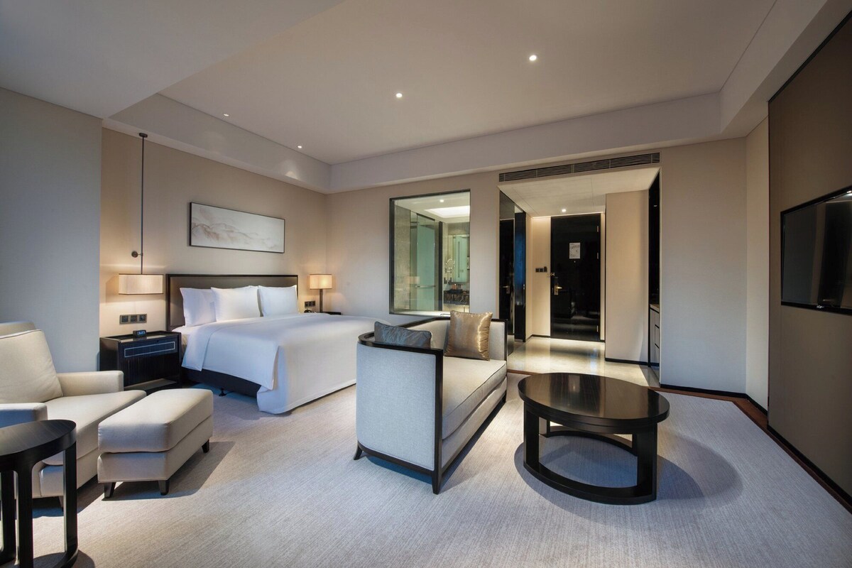 Una habitación de hotel moderna con cama, zona de estar y televisor.