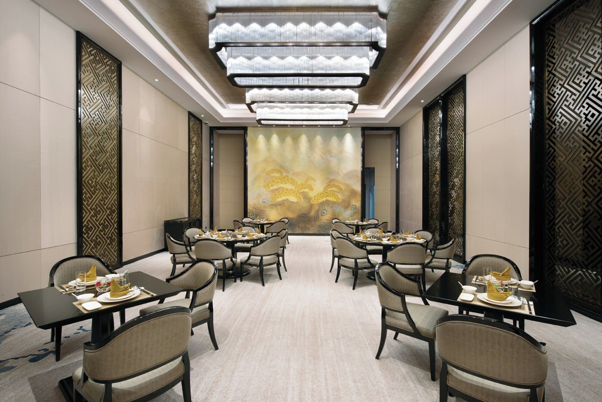 Una sala conferenze con soffitto alto, lampadari moderni e un grande murale decorativo sulla parete di fondo.