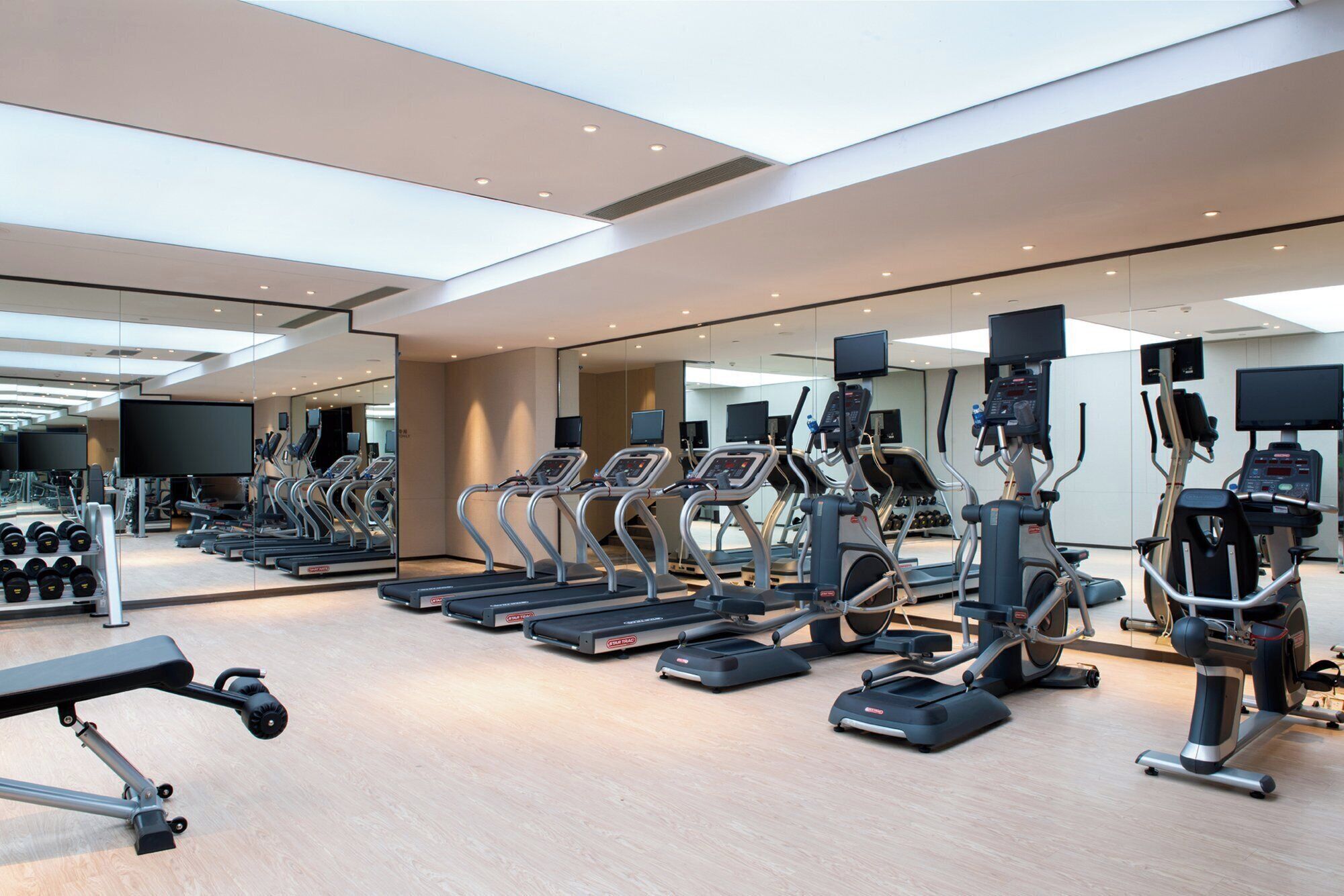 Un gimnasio con cintas de correr, elípticas y pesas libres.