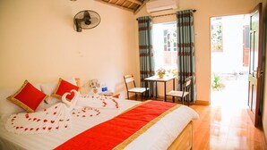 A hotel room with a bed, a fan, a table with chairs, and a view of the outside. - Tam Coc Riverside homestay (Nam Hoa Lu)