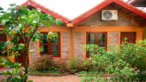 A brick house with a red roof, a window, and a potted plant. - Tam Coc Riverside homestay (Nam Hoa Lu)