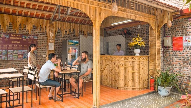 A restaurant with bamboo decor, a reception desk, and tables for guests. - Tam Coc Riverside homestay (Nam Hoa Lu)