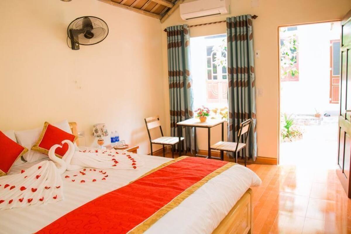 Une chambre d’hôtel avec un lit, un ventilateur, une table avec des chaises et une vue sur l’extérieur.