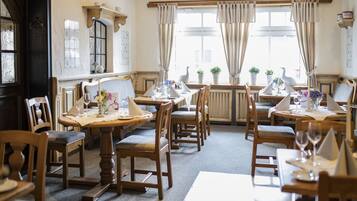 A dining area with wooden tables and chairs, set for a meal.