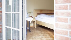 Een slaapkamer met een houten bed, een nachtkastje met een lamp en een raam met gordijnen.
