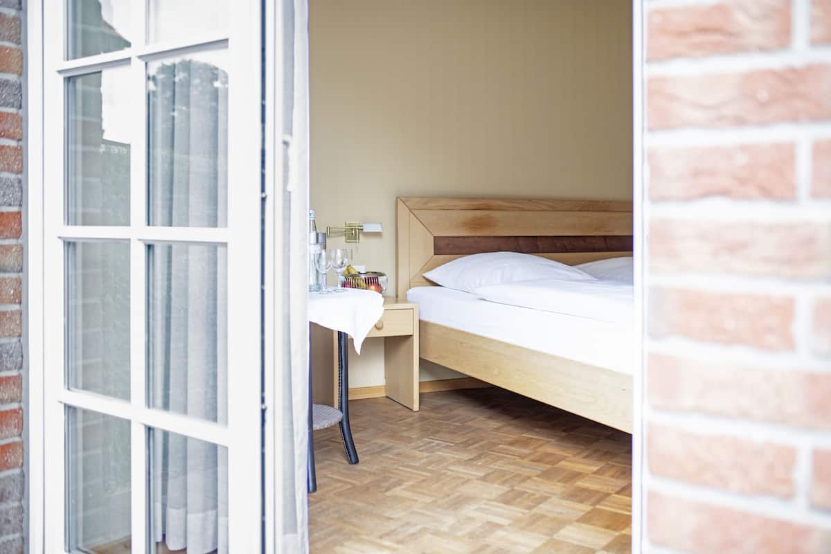 Une chambre à coucher avec un lit en bois, une table de chevet avec une lampe et une fenêtre avec des rideaux.