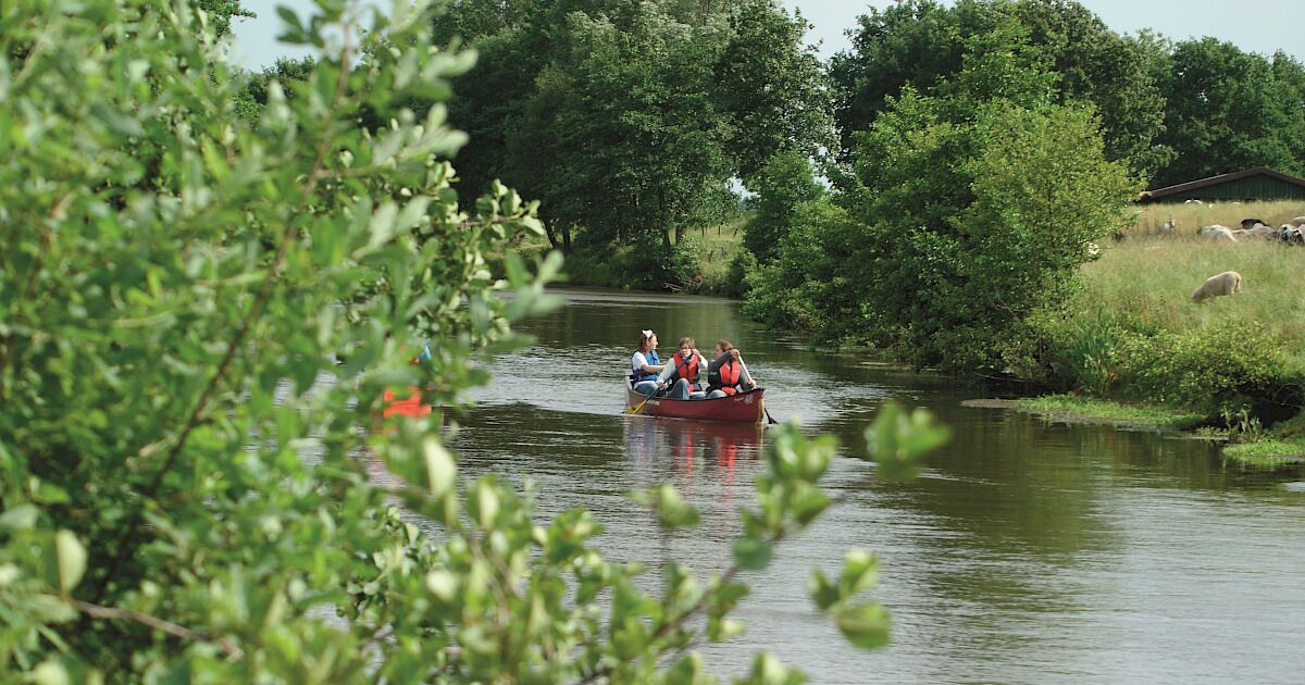 A narrow waterway with a boat carrying three people.