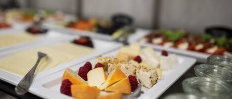 A buffet with various food items including cheese, fruits, and nuts.