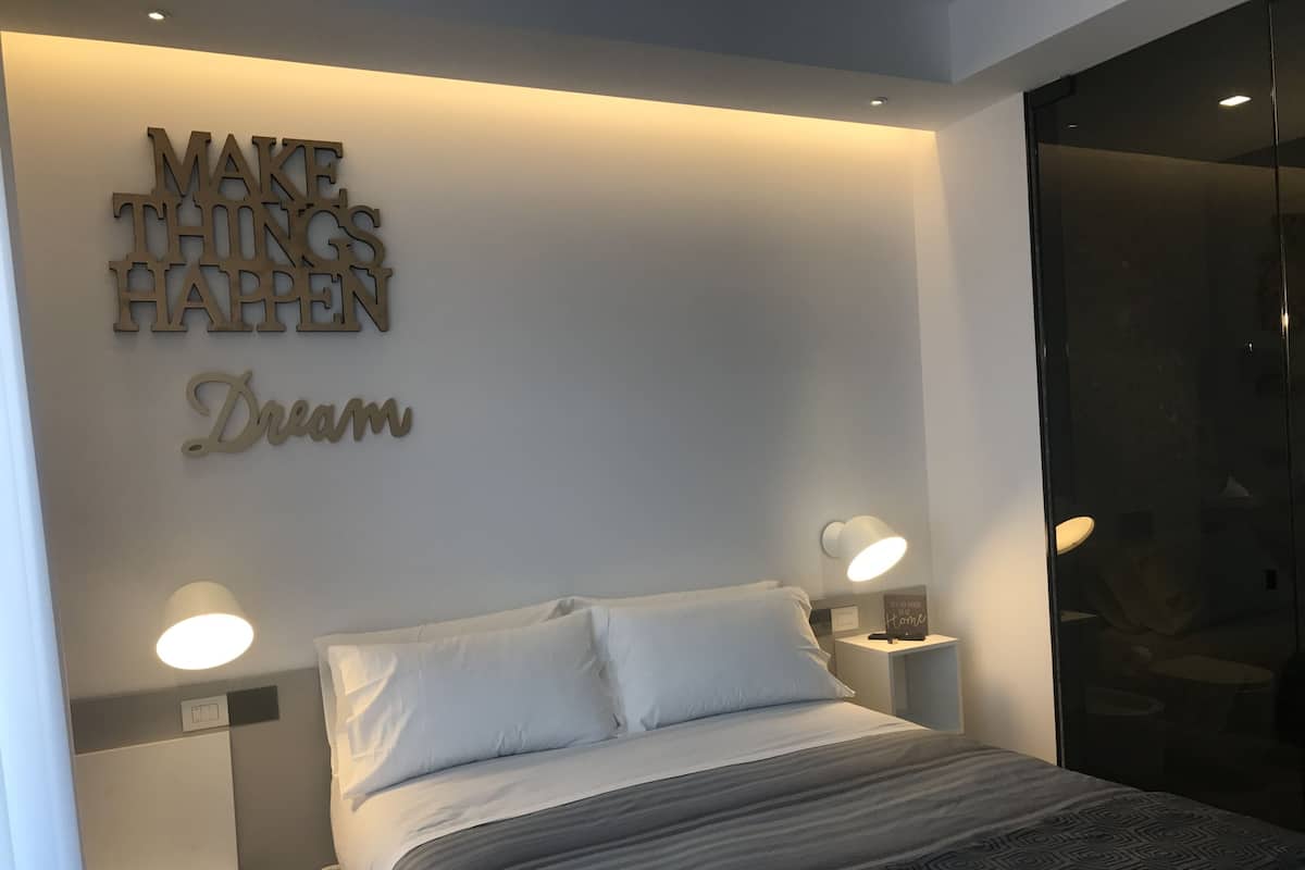 Un dormitorio moderno con una cama, dos mesitas de noche, una lámpara de pared y decoración inspiradora.