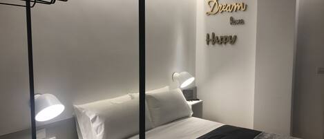 A neatly arranged bedroom with a bed, bedside lamps, a wall-mounted shelf, and decorative wall art.