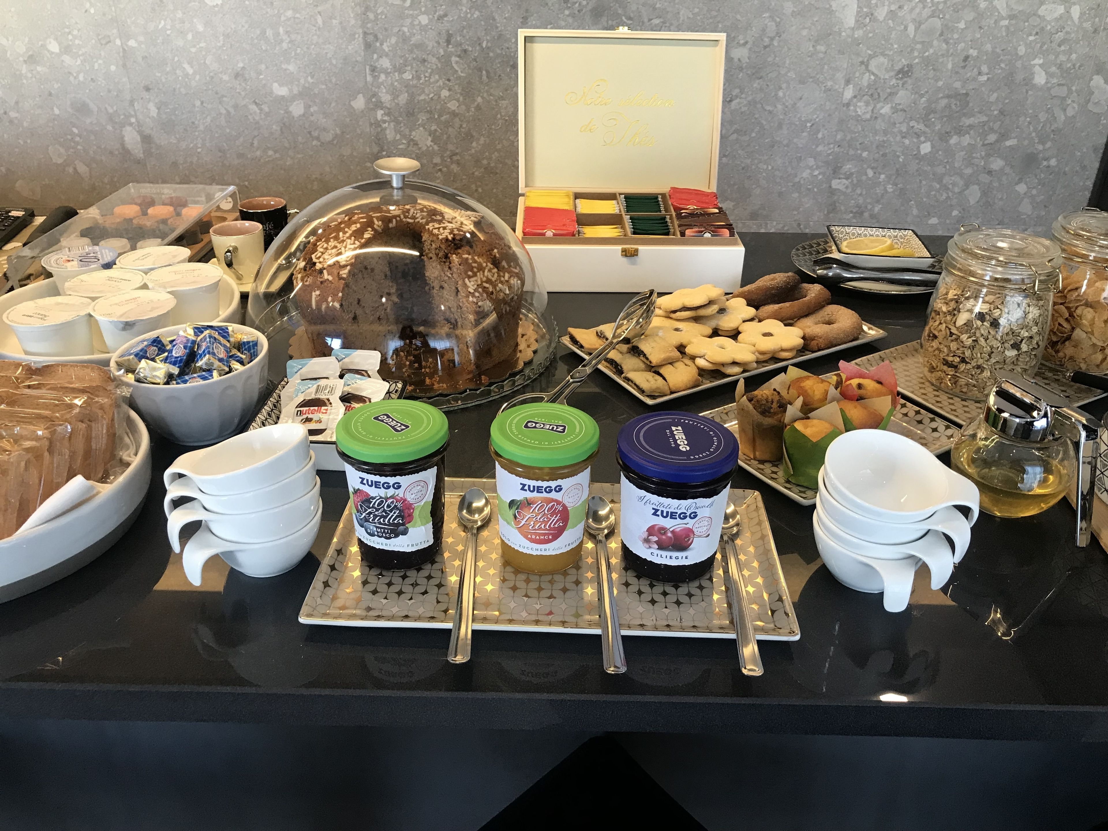 Ein Buffet mit verschiedenen Speisen, darunter Gläser mit Zuegg-Marmelade, Gebäck und Kuchen.