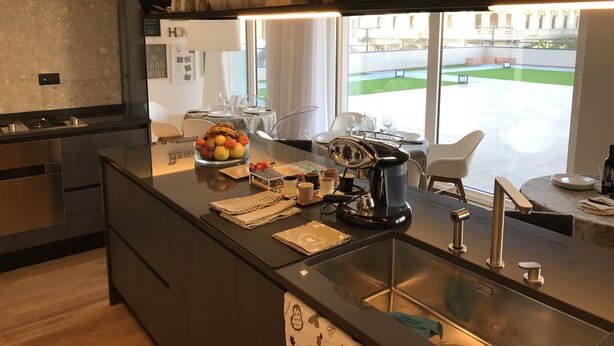 Una cocina moderna con una isla central, electrodomésticos de acero inoxidable y vistas a un espacio verde exterior.