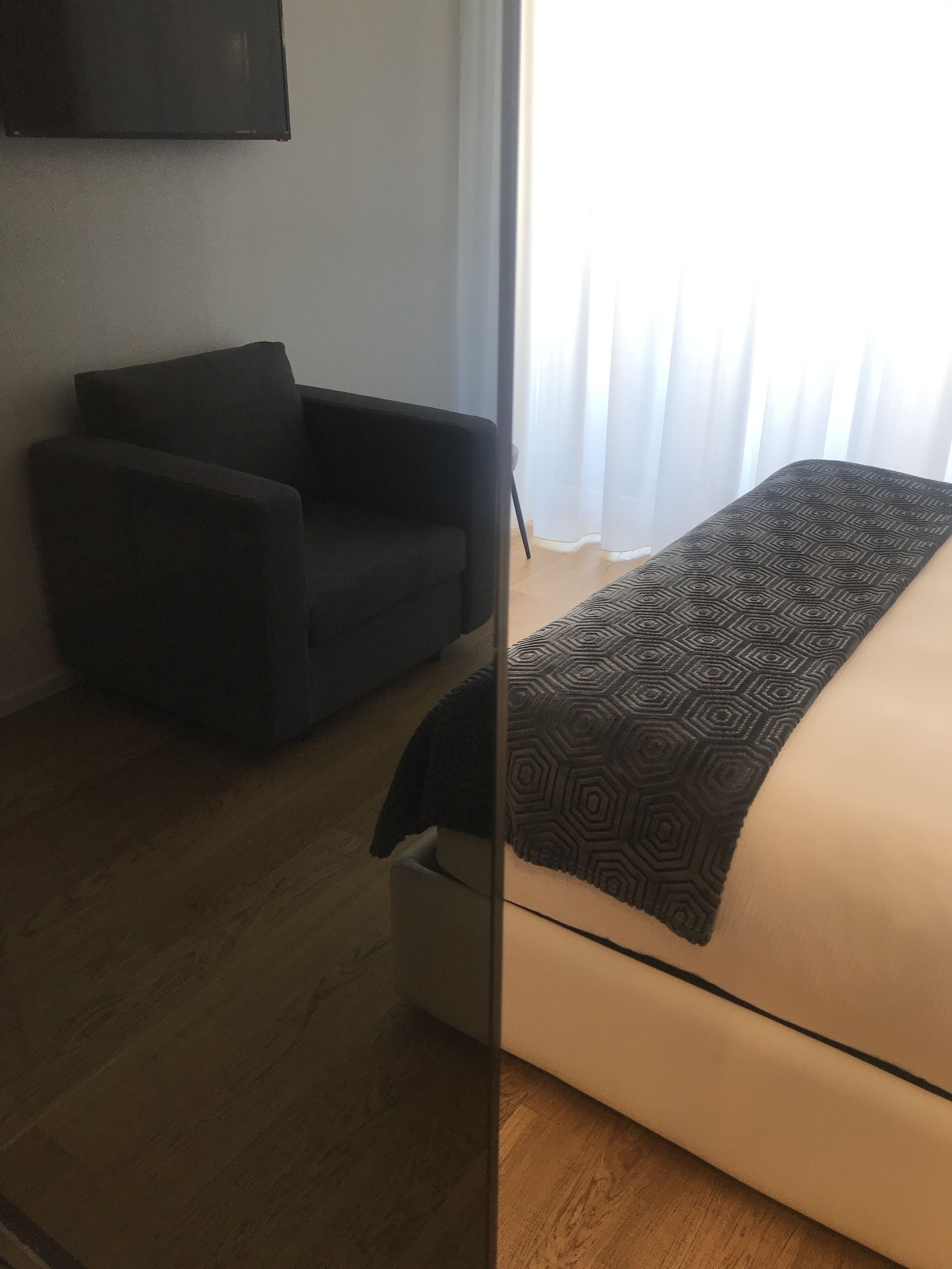 A hotel room with a bed, a chair, and a small table.